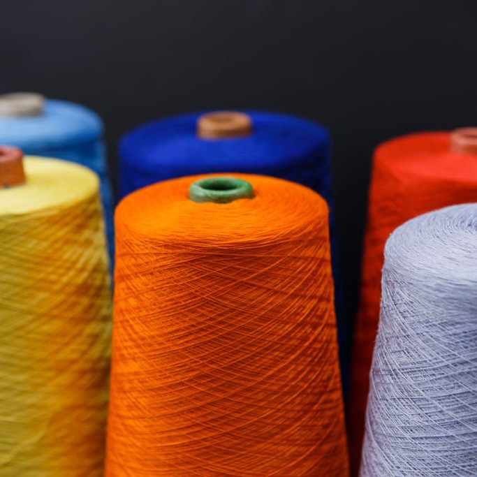 Closeup blue, azure, red, yellow, orange and lavender colors spools of sewing thread on black background