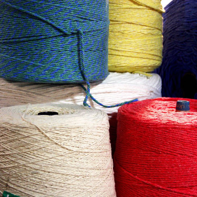 Side view of large spools of colored yarn stacked and side by side